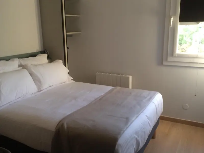 Une chambre lumineuse avec un grand lit recouvert d'une couverture blanche.