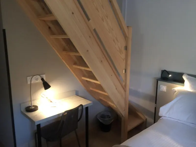 Une chambre avec un bureau et un escalier en bois.