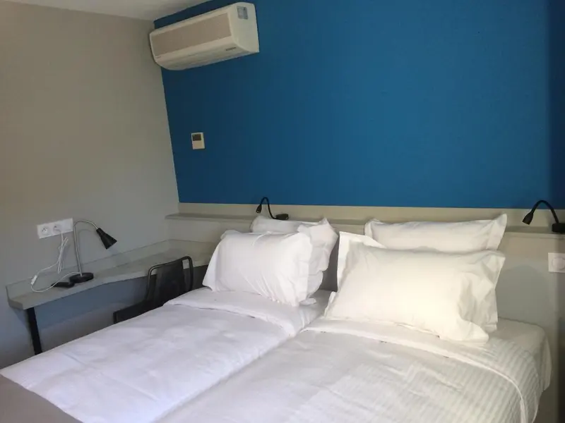 Un lit blanc est fait dans une chambre aux murs bicolores.