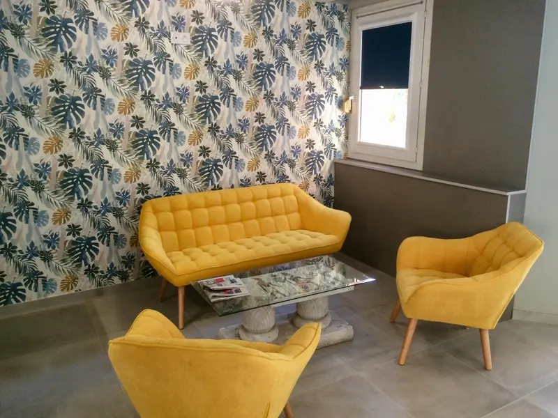 Un espace de détente intérieur avec un canapé jaune et des fauteuils.