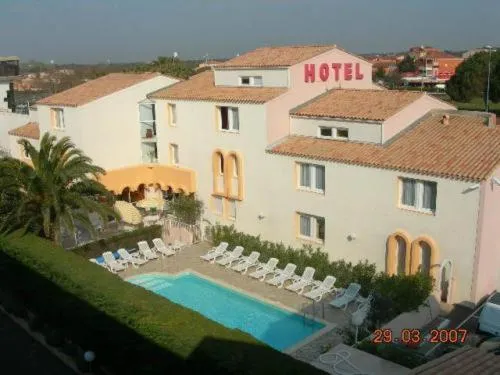 Bâtiment rose avec piscine et transats en contrebas.