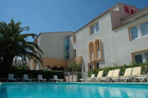 Façade d'un bâtiment blanc et ocre avec une piscine au premier plan et des transats.