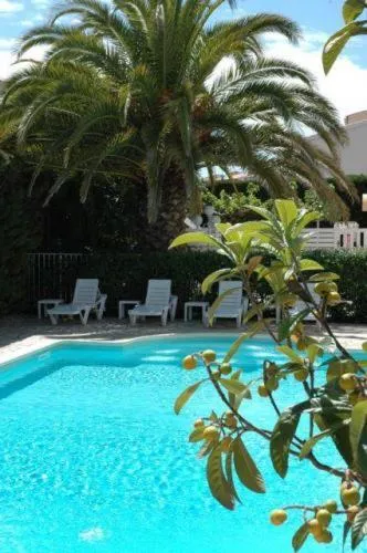 Transats et parasols bordent une piscine turquoise au milieu d'une végétation luxuriante.