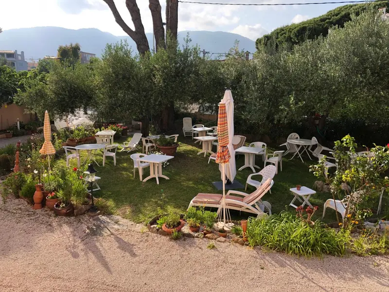 Terrasse verdoyante avec tables et chaises en fer forgé.