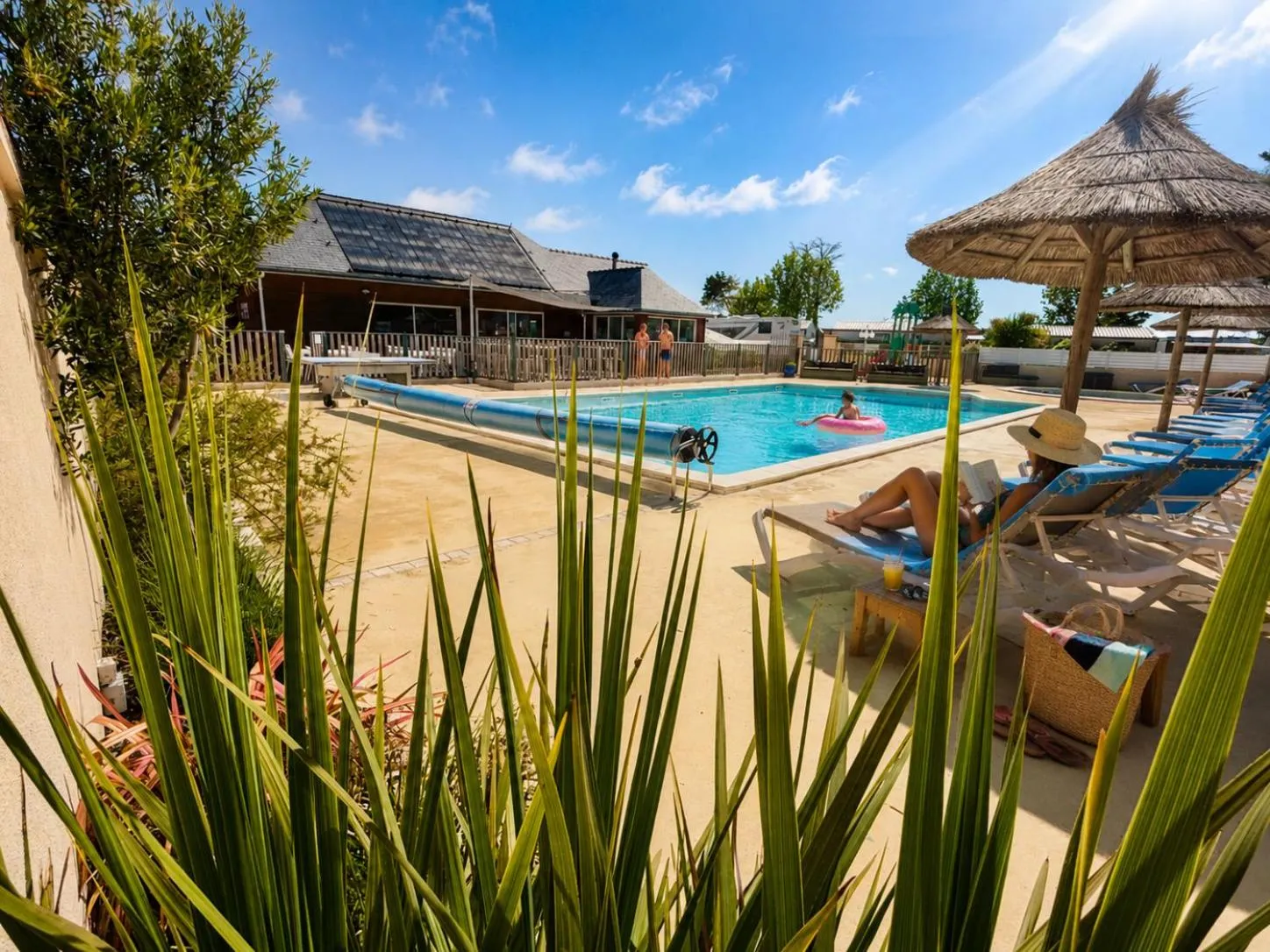 Une piscine ensoleillée avec des transats et des parasols.