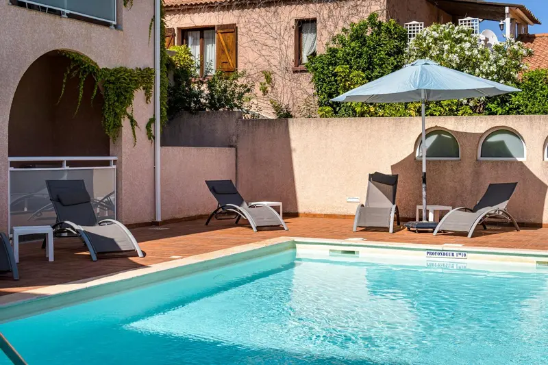 Transats gris disposés autour d'une piscine ensoleillée.