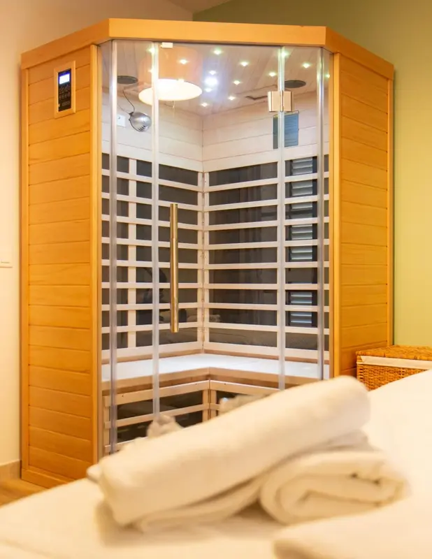 Cabine de sauna en bois clair avec serviettes pliées au premier plan.