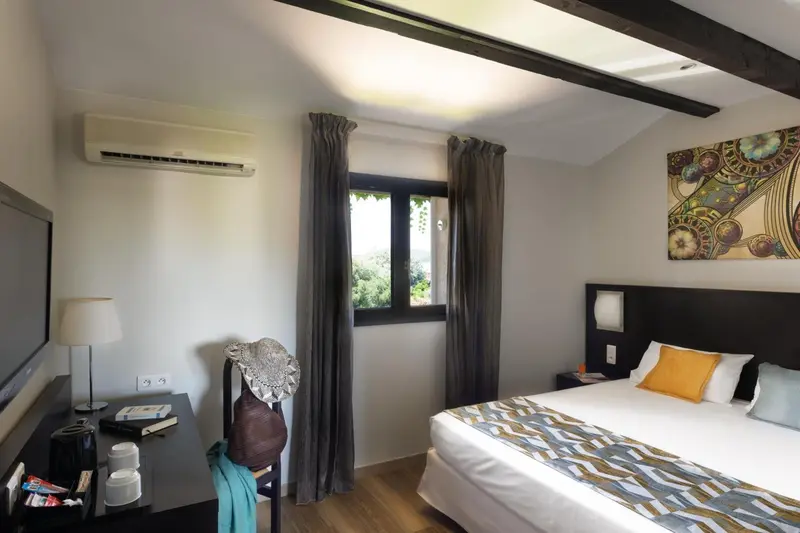 Une chambre lumineuse avec un lit fait et un bureau.
