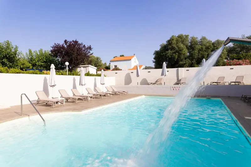 Transats alignés au bord d'une piscine avec cascade.