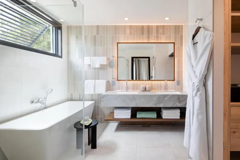 Une salle de bain lumineuse avec baignoire et double vasque.