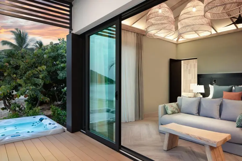 Une chambre avec un salon et un accès à une terrasse avec jacuzzi.