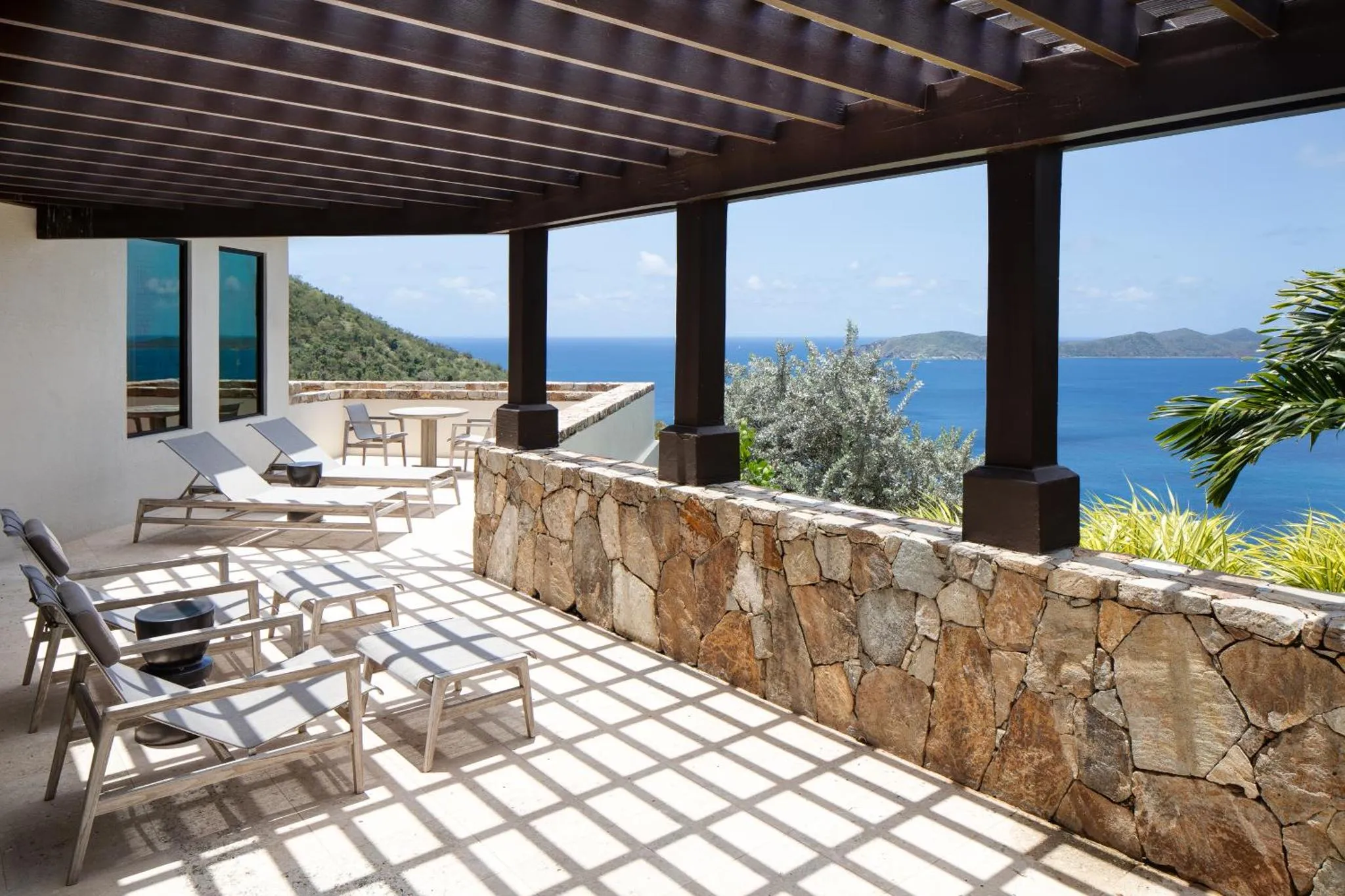 Terrasse carree avec transats blancs donnant sur la mer.