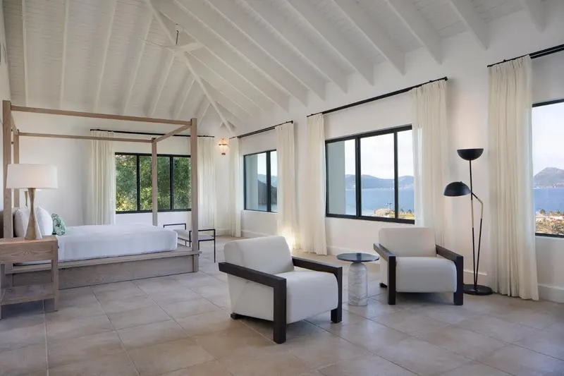 Une chambre lumineuse avec un lit à baldaquin et vue sur la mer.
