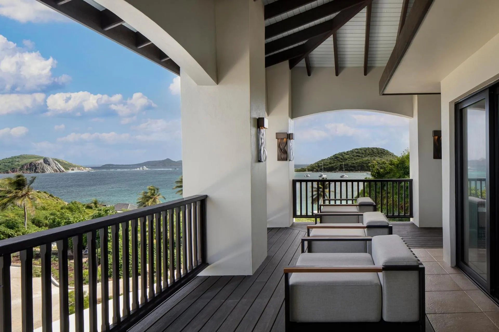 Terrasse ombragée avec mobilier d'extérieur donnant sur une vue mer.