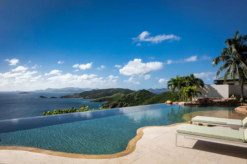 Une piscine à débordement surplombe une côte rocheuse et la mer.