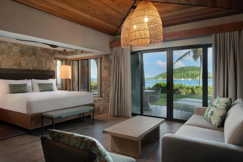 Une chambre lumineuse s'ouvre sur une vue sur la mer par de grandes baies vitrées.