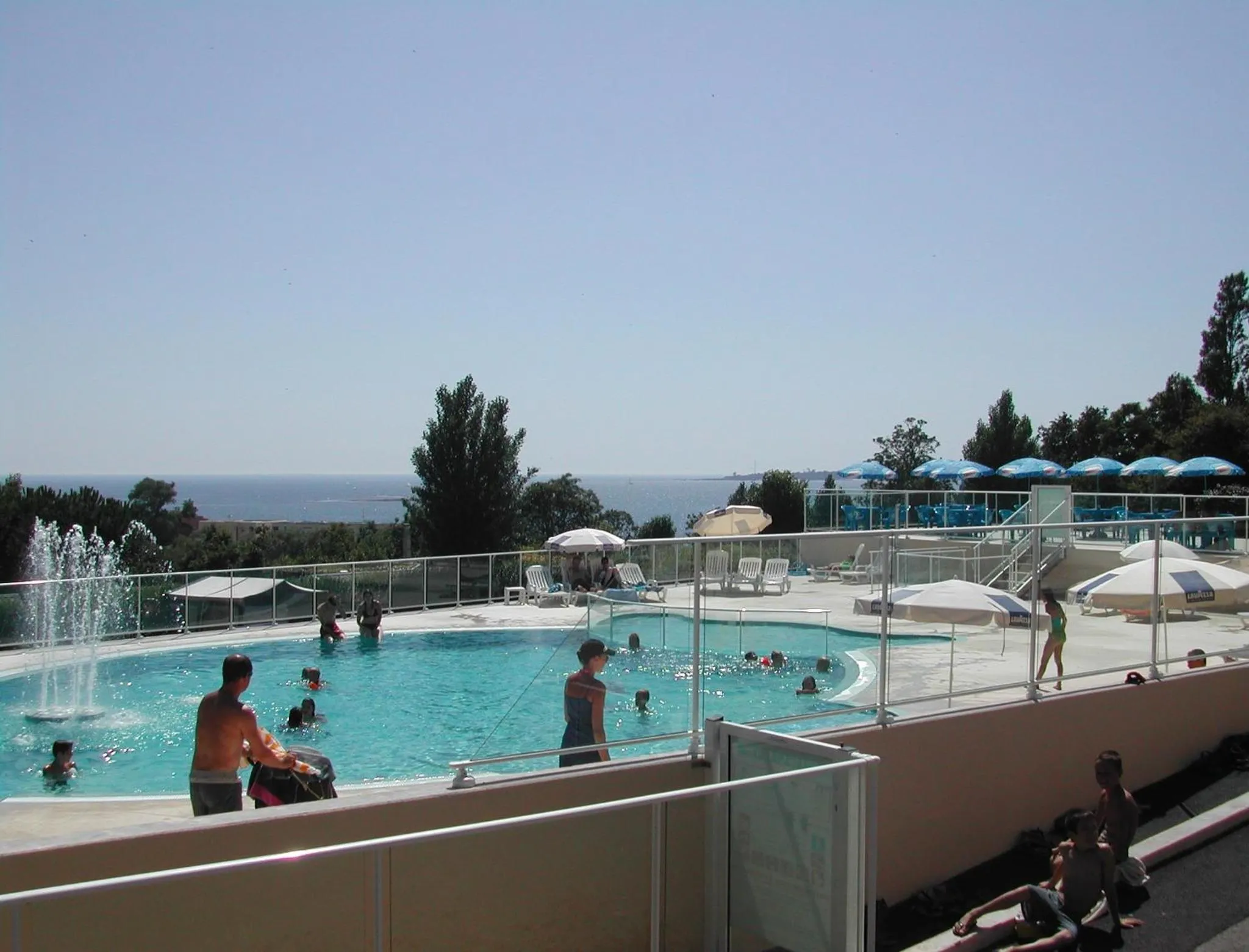 Une piscine avec des personnes se baignant et des transats en bord de mer.