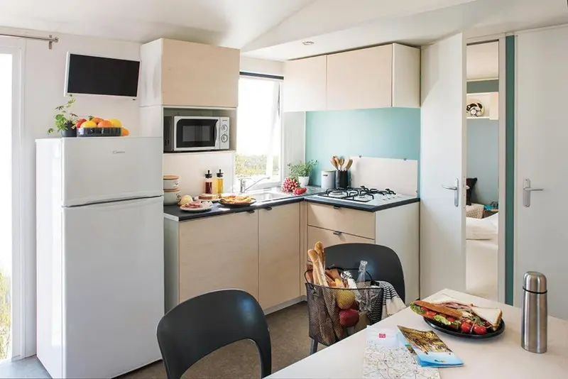 Une cuisine moderne avec un réfrigérateur, un micro-ondes et une table à manger.