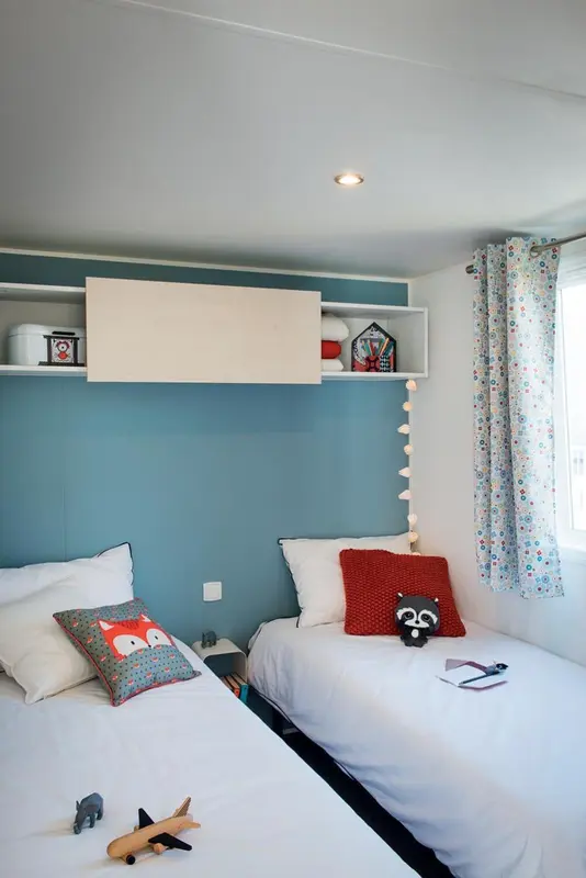 Une chambre lumineuse avec deux lits simples et une décoration colorée.