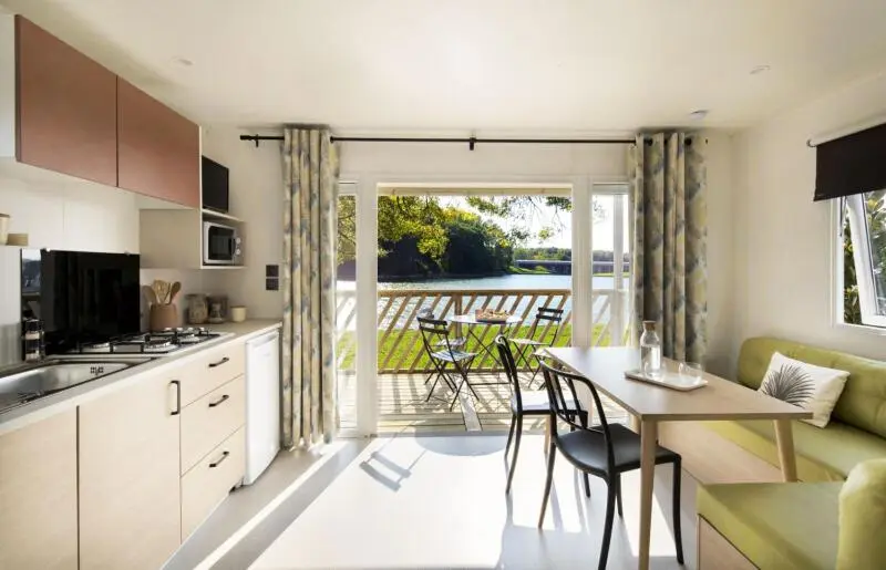 Une cuisine ouverte donne sur une terrasse avec une table et des chaises.