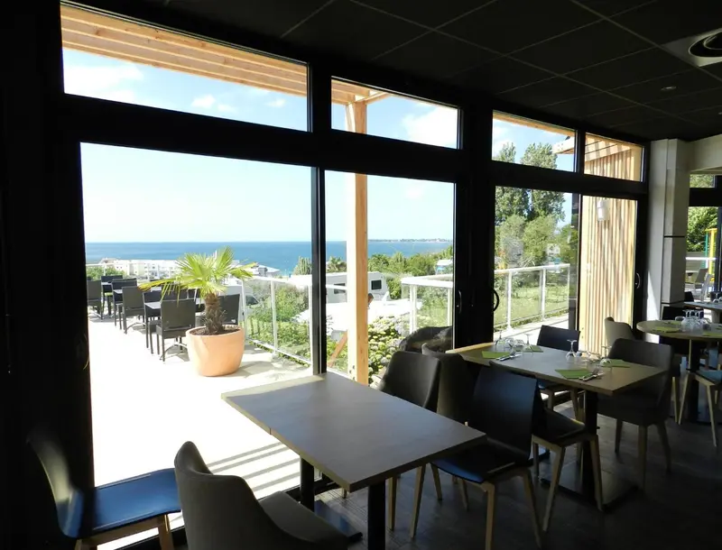 Une salle lumineuse donne sur une terrasse avec vue sur la mer.