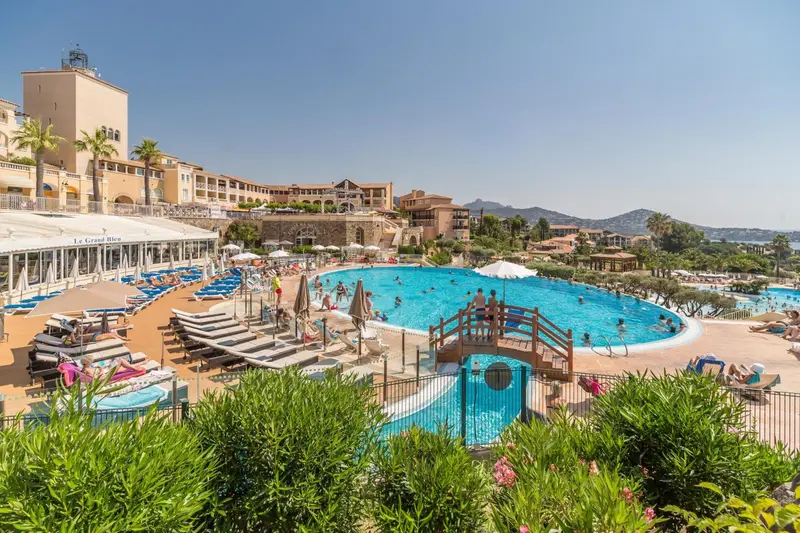 Vue d'une piscine d'hôtel avec des transats et un ponton.