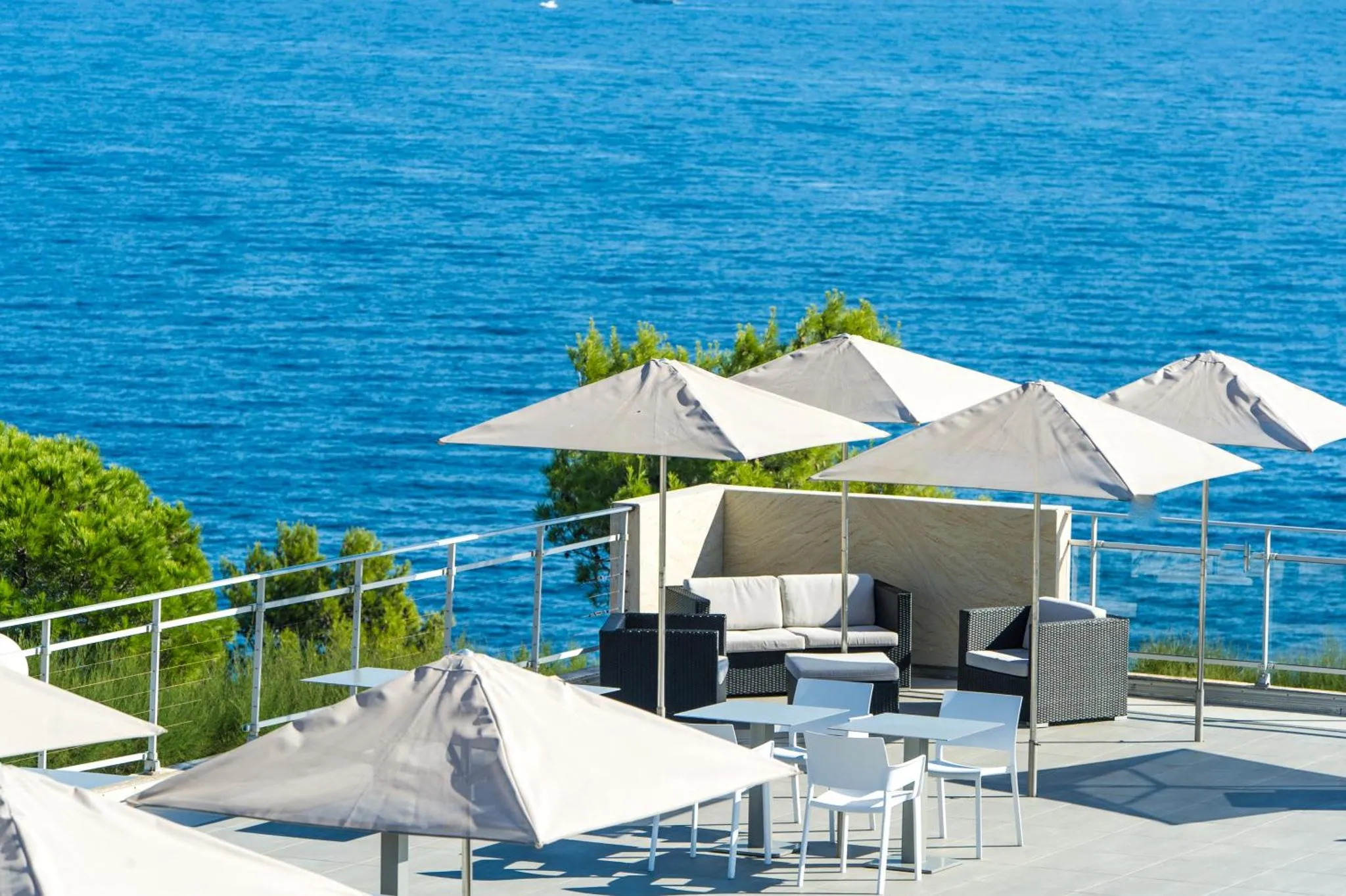 Terrasse aménagée avec des parasols et des meubles de jardin offrant une vue sur la mer.