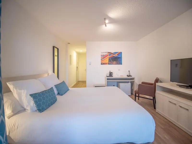 Une chambre lumineuse avec un lit fait et un espace détente.