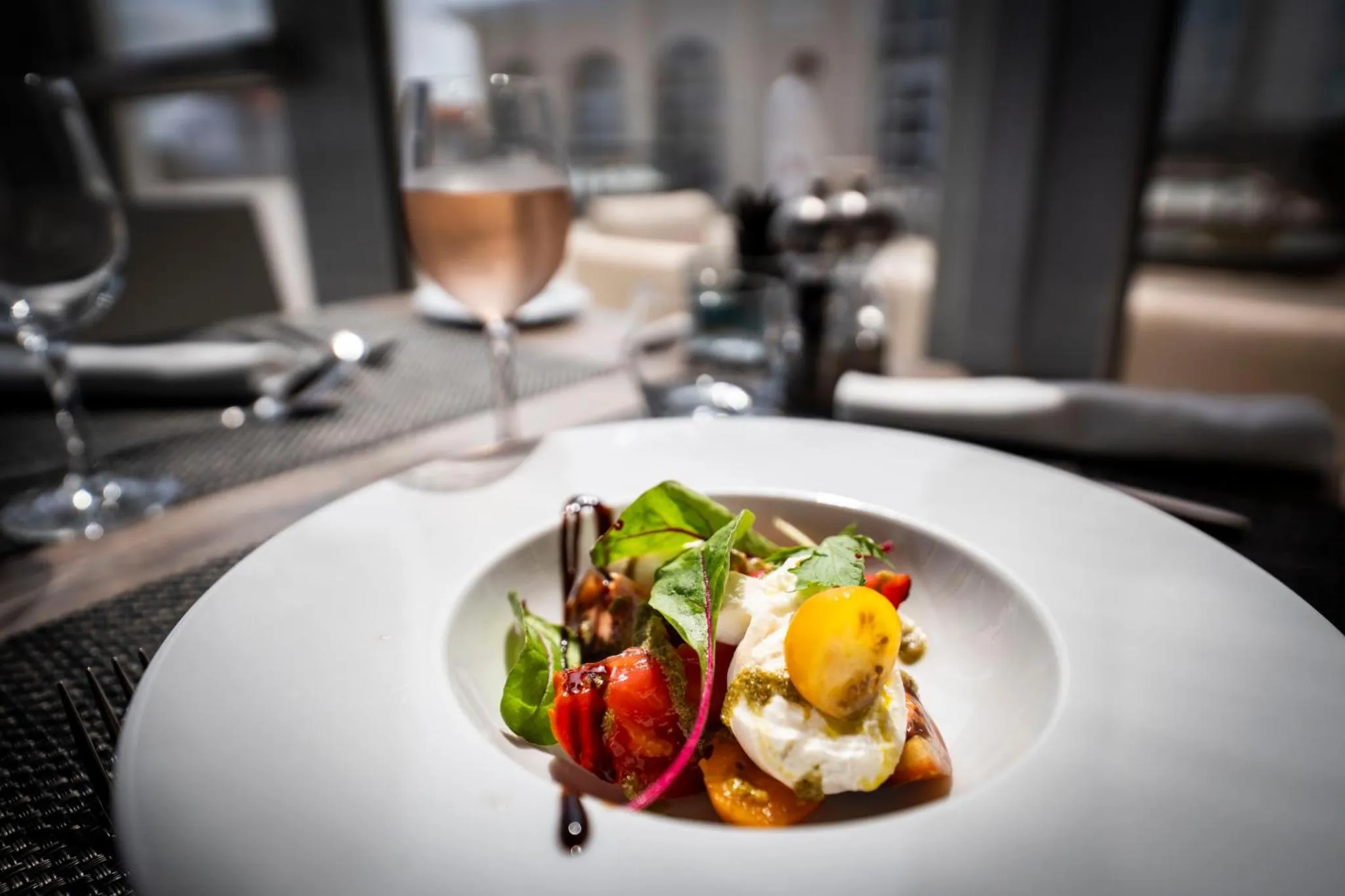 Une assiette de salade garnie d'un œuf au plat est mise en valeur sur une table dressée.