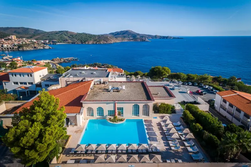 Vue aérienne d'un complexe hôtelier avec piscine et accès à la mer.