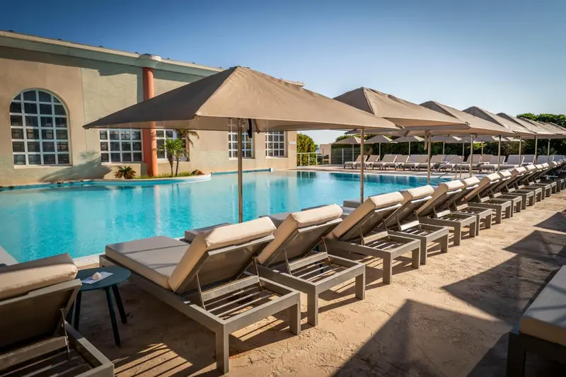 Transats alignés au bord d'une piscine ensoleillée.