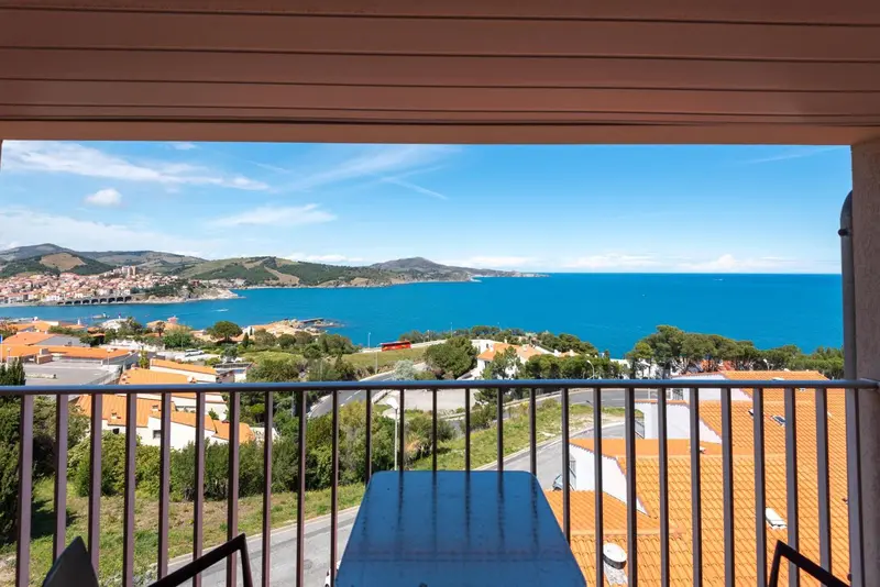 Vue dégagée sur la mer et les collines depuis un balcon.