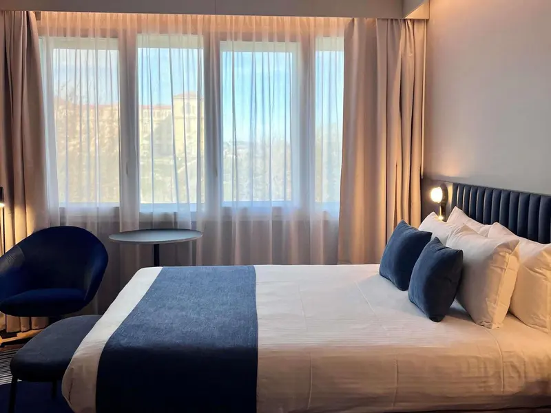 Une chambre avec un grand lit et un fauteuil près d'une fenêtre.