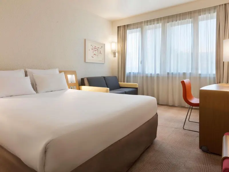 Une chambre lumineuse avec un lit double et un coin salon.