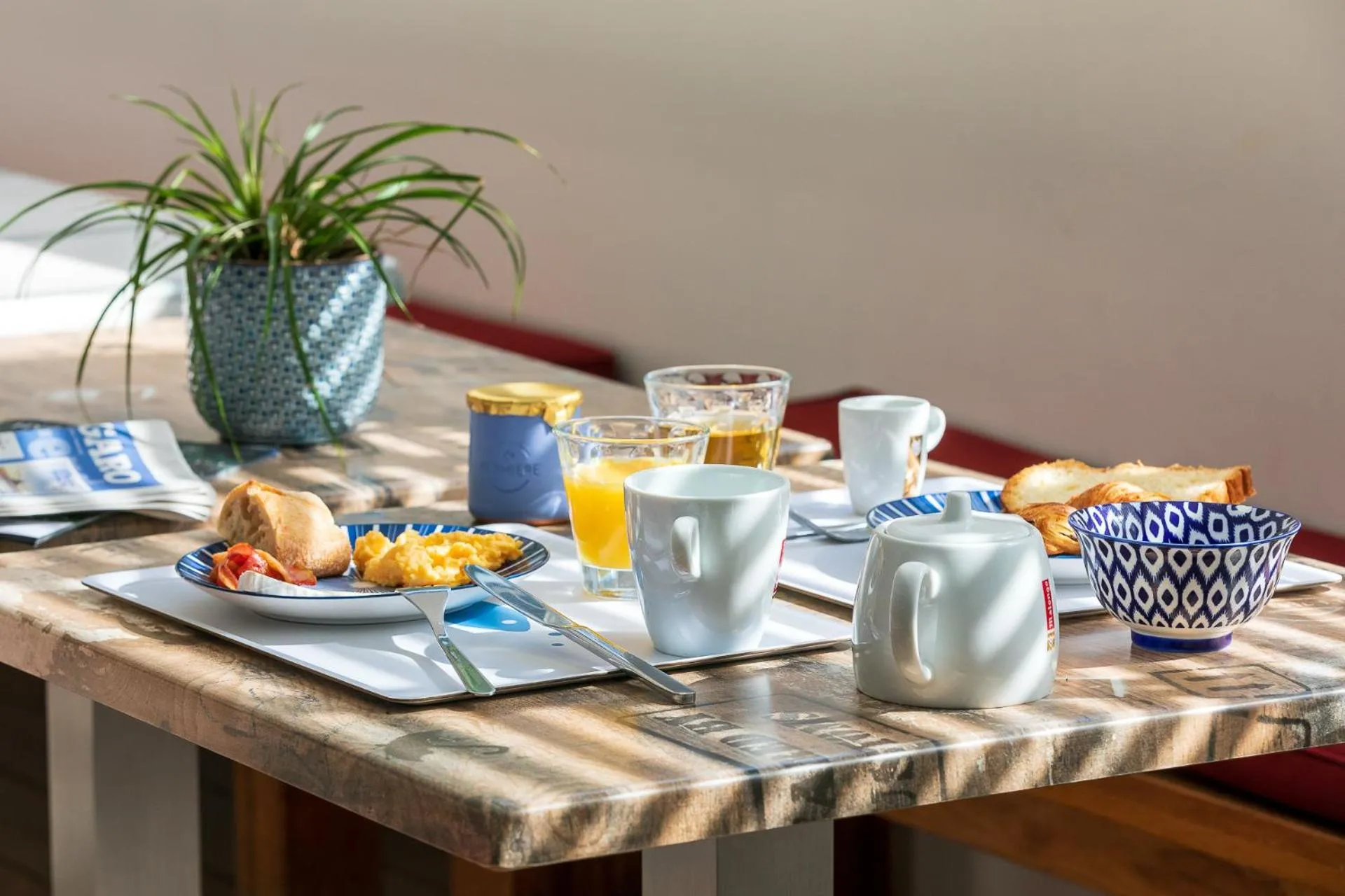 Une table est dressée avec un petit-déjeuner composé d'œufs, de pain et de boissons.