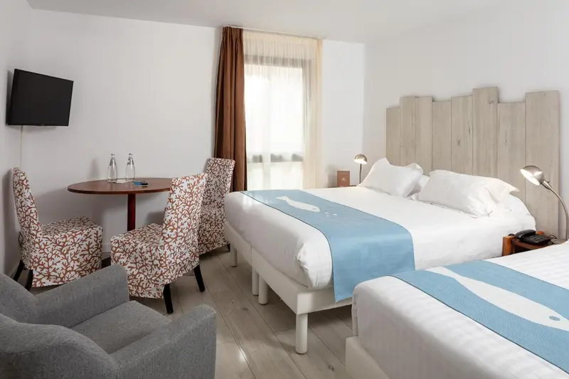 Une chambre lumineuse avec un lit double et un coin salon.