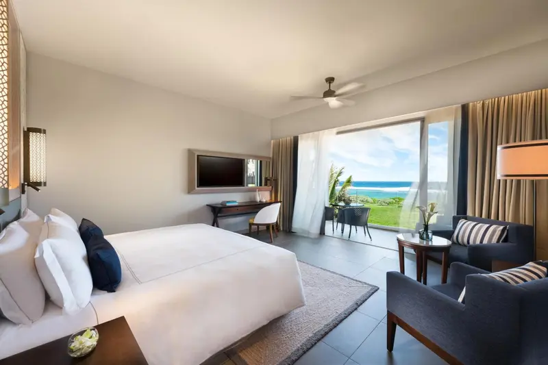 Chambre lumineuse avec un grand lit et vue sur la mer.