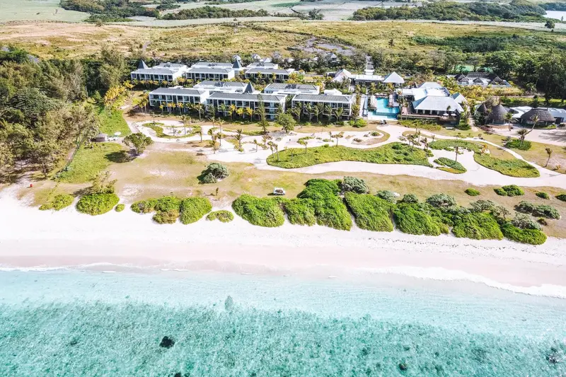 Vue aérienne d'un complexe hôtelier bordant une plage de sable clair et une mer turquoise.