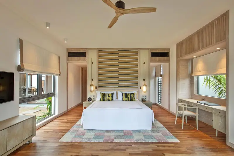 Une chambre lumineuse avec un grand lit et un tapis coloré.