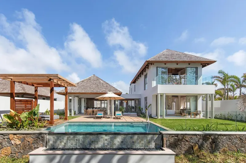 Bâtiment blanc à deux étages avec piscine et végétation tropicale.