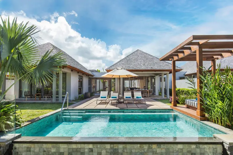 Petite piscine turquoise devant des villas aux toits en pente.