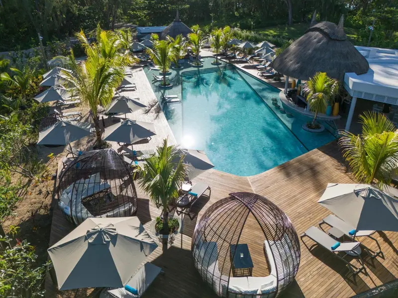Vue aérienne d'une piscine bordée de transats et de palmiers.