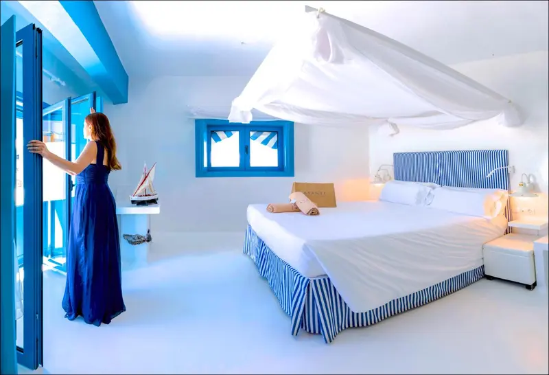 Une femme se tient à l'entrée d'une chambre lumineuse avec un lit à baldaquin.
