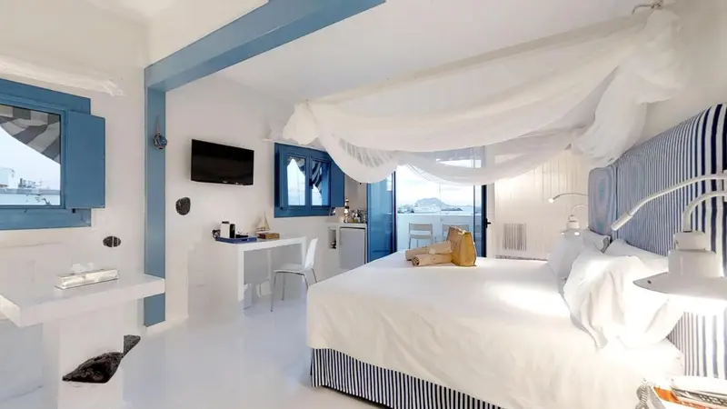 Chambre lumineuse avec un grand lit à baldaquin et une vue sur la mer.