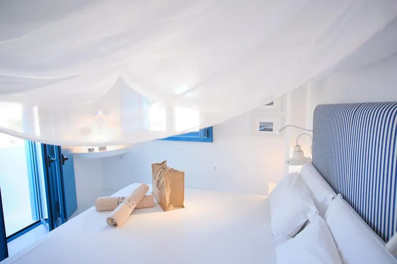 Une chambre lumineuse avec un lit à baldaquin et des oreillers blancs.