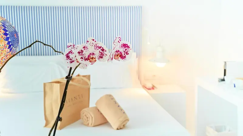 Fleurs roses et blanches sur un lit blanc dans une chambre lumineuse.