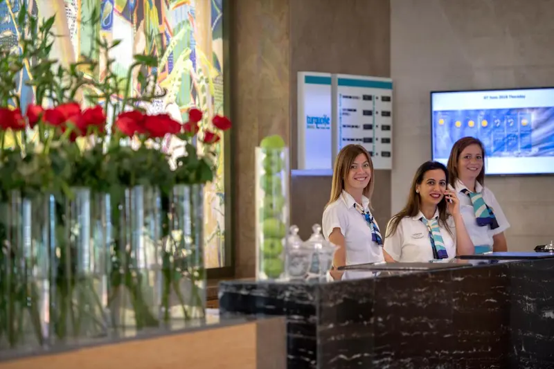 Un comptoir d'accueil fleuri avec du personnel souriant.