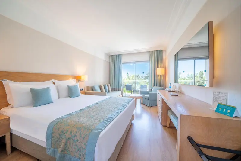 Une chambre lumineuse avec un grand lit et un coin salon.