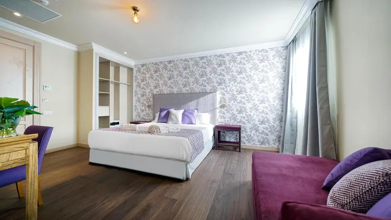 Une chambre lumineuse avec un grand lit et un coin salon.