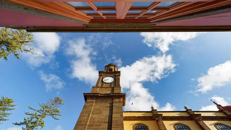 Vue d'une tour d'horloge sous un ciel bleu nuageux.